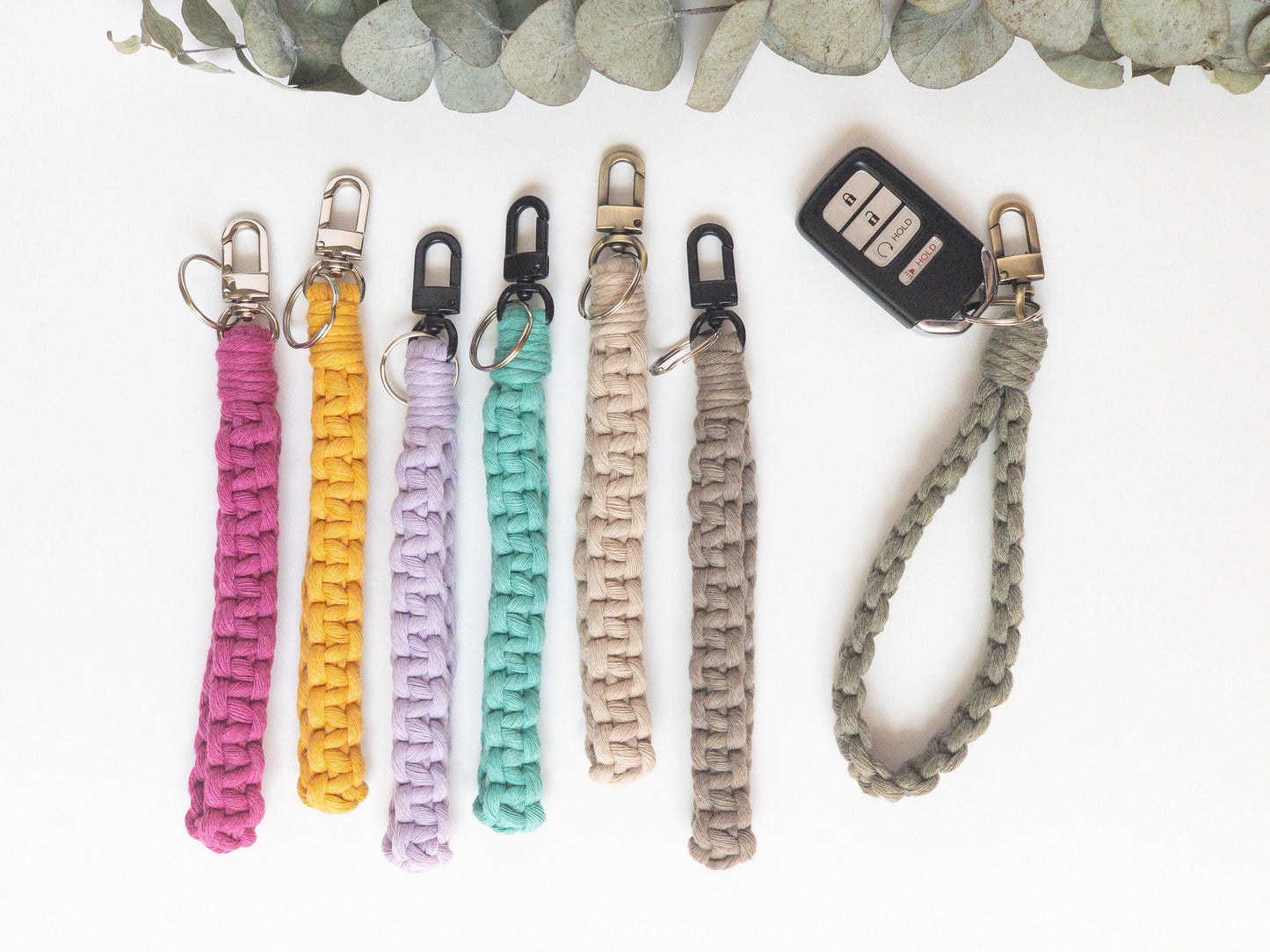 Wristlet Style Macrame keychain in a straight square knot pattern. Shown in 7 colors, hot pink, yellow, lavender, aqua, beige, taupe and sage green. Brass, silver and smoke colored hardware. Keyfob attached to sage green keychain.