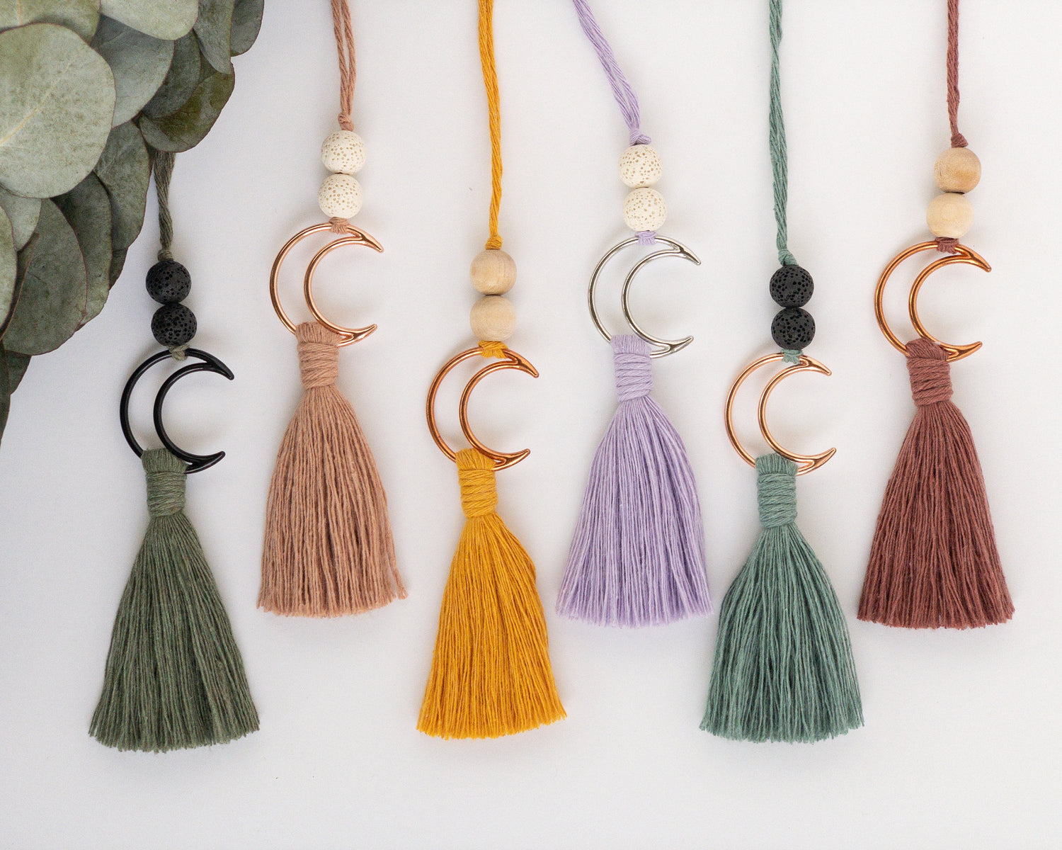 Decor piece to hang from the rearview mirror of your car. Features a metal crescent moon with colorful brushed macrame cord tassel. Some have a wood bead at the top of the ring, others have a black or white lava bead.